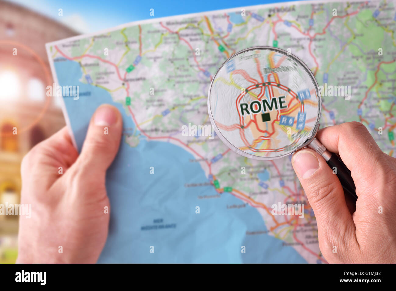 Mains de ramasser une carte de Rome et à la recherche d'un endroit à l'aide d'une loupe avec monument représentant dans l'arrière-plan Banque D'Images