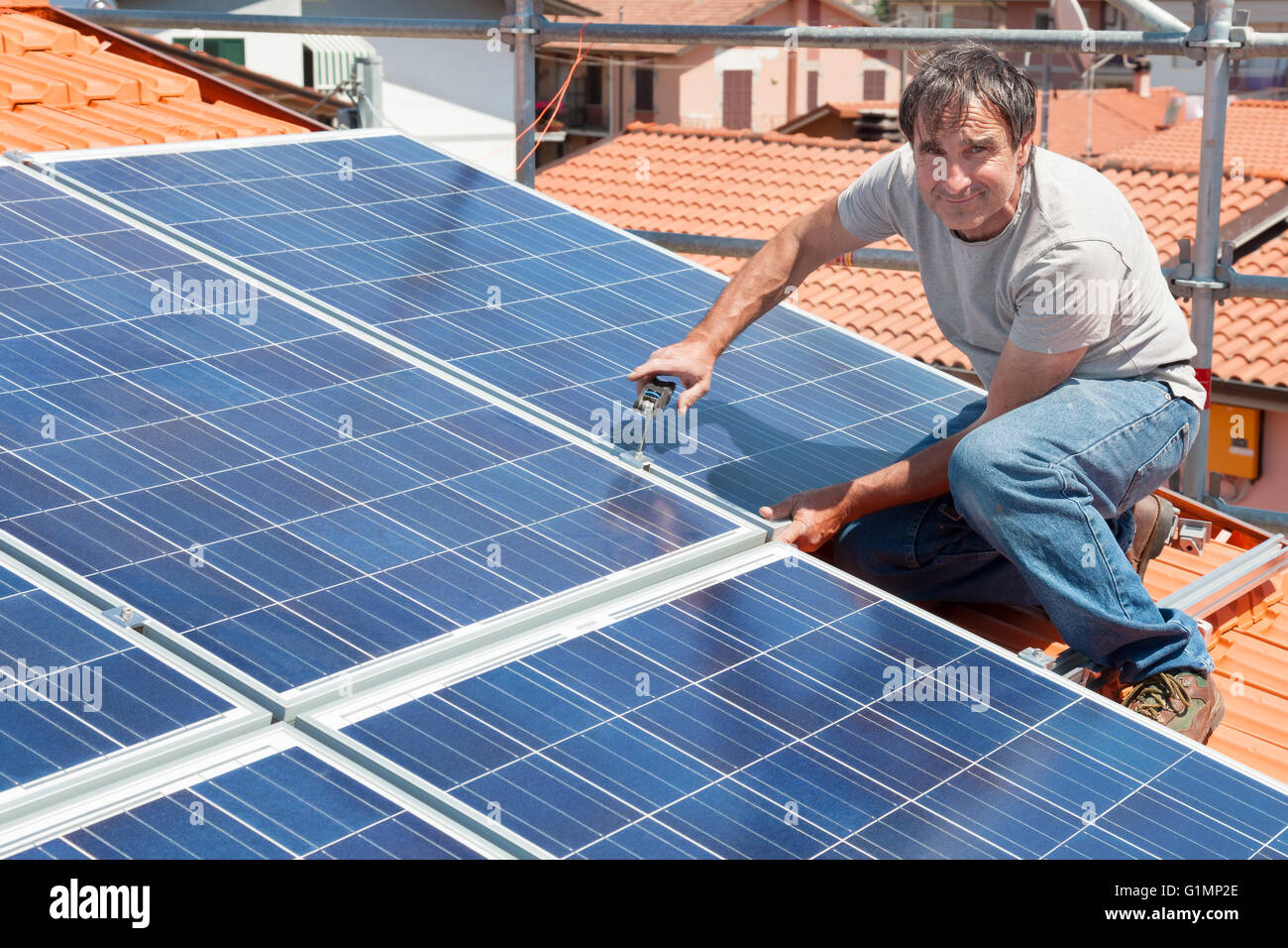 L'installation de l'homme de l'énergie de remplacement des panneaux solaires photovoltaïques sur le toit Banque D'Images