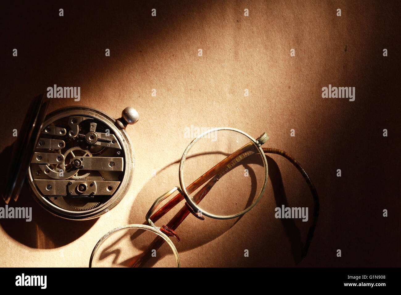 Ancienne montre de poche fermée près de spectacles sur fond de papier brun Banque D'Images