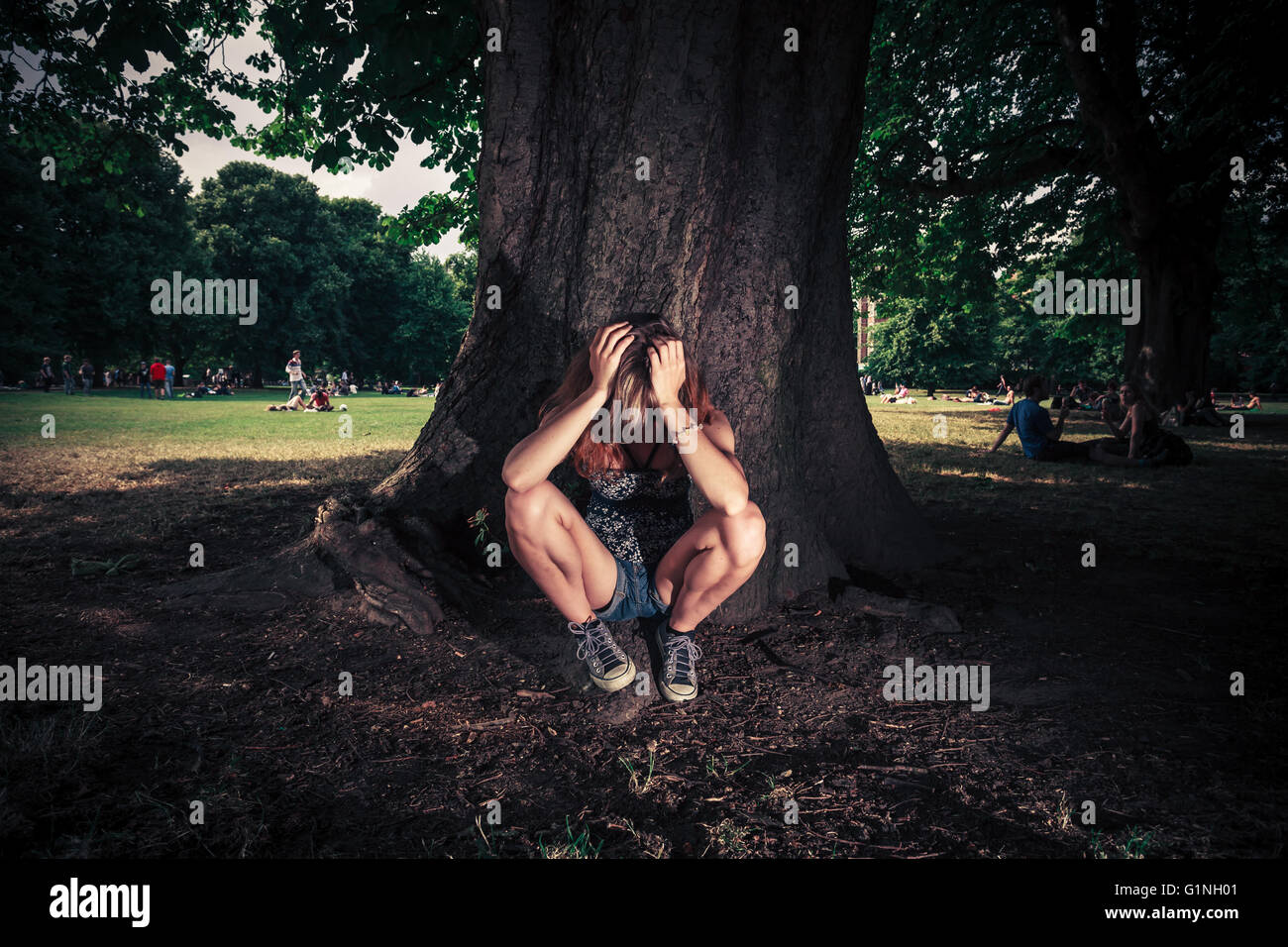 Un appui sur une jeune femme fatiguée est assis sous un grand arbre dans le parc Banque D'Images