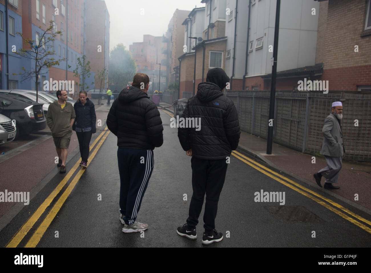 Les habitants regardent le fire Crew s'attaquer à un incendie dans un immeuble d'appartements à Brodlove Lane à Wapping, Londres, Royaume-Uni. Selon les sources, l'incendie était peut-être due à des bouteilles de gaz qui ont été dans une cour de constructeurs à la base du bâtiment. Un résident local a dit qu'il y avait souvent des incendies dans cette région, bien qu'il ne savait pas quelle en était la cause. Banque D'Images