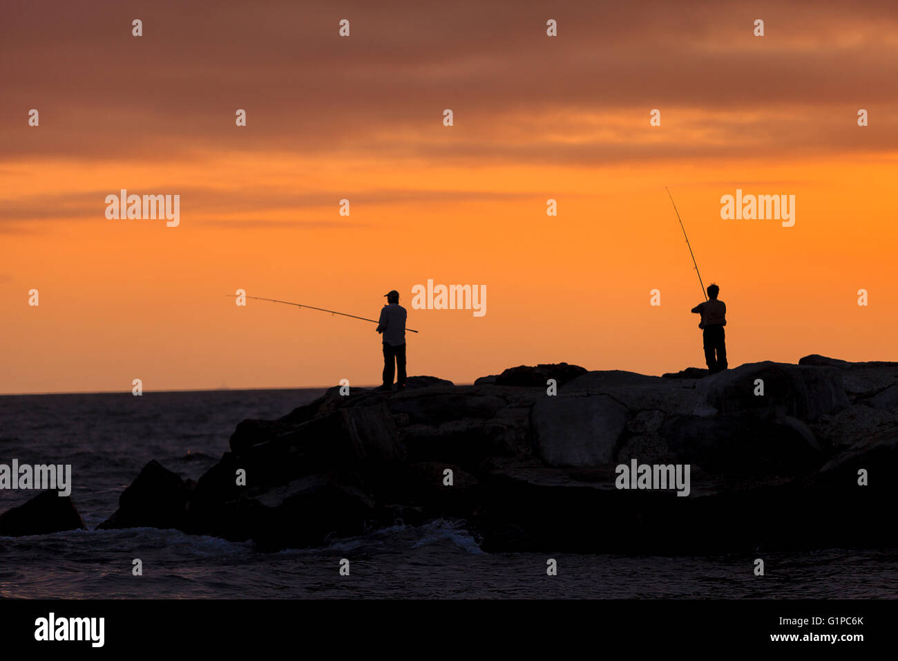 Silhouette d'hommes sur le quai de pêche au large de l'Île de Balboa, Newport Beach au coucher du soleil dans le sud de la Californie Banque D'Images