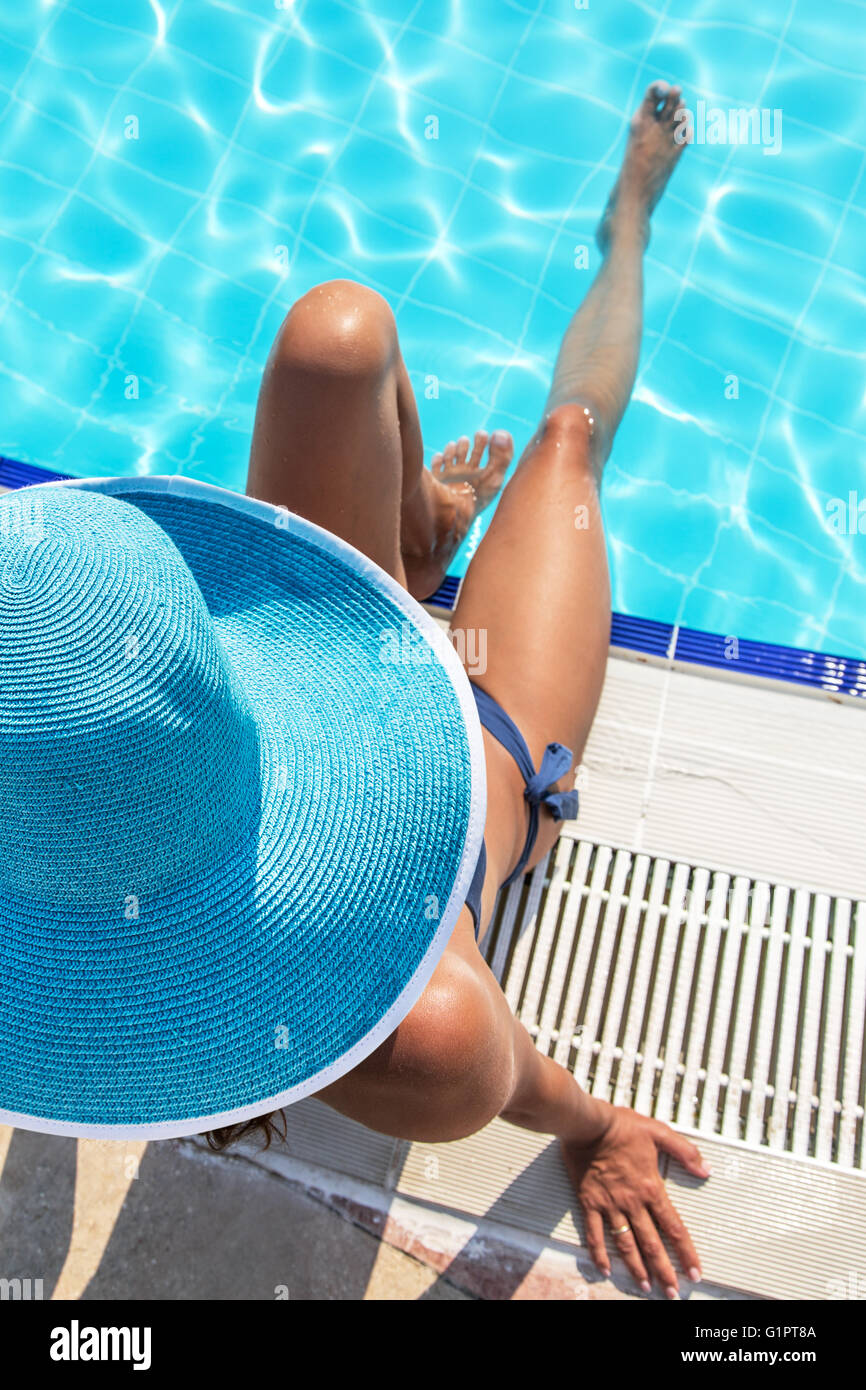 Femme assise sur le bord de piscine. Banque D'Images