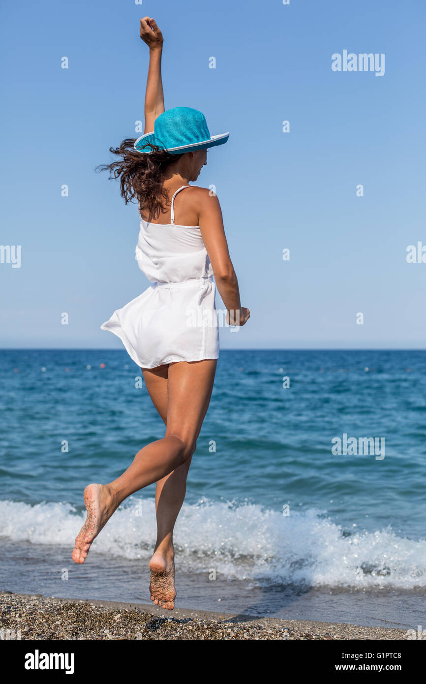 Femme sautant sur la plage près du bord de l'eau. Banque D'Images