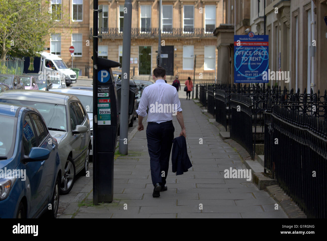 Young male office worker après le travail avec veste sur une journée chaude sur la rue géorgienne de la ville avec des signes Glasgow, Écosse, Royaume-Uni. Banque D'Images