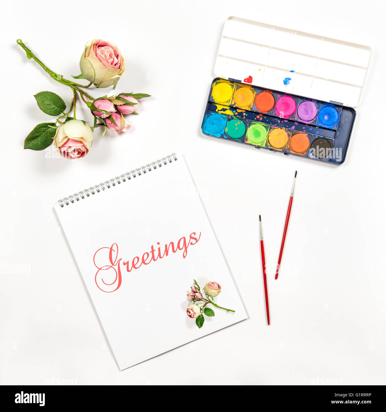 Mise à plat avec un carnet de croquis, aquarelle, pinceaux, papier, fleurs de rose. Concept de carte de vœux Banque D'Images