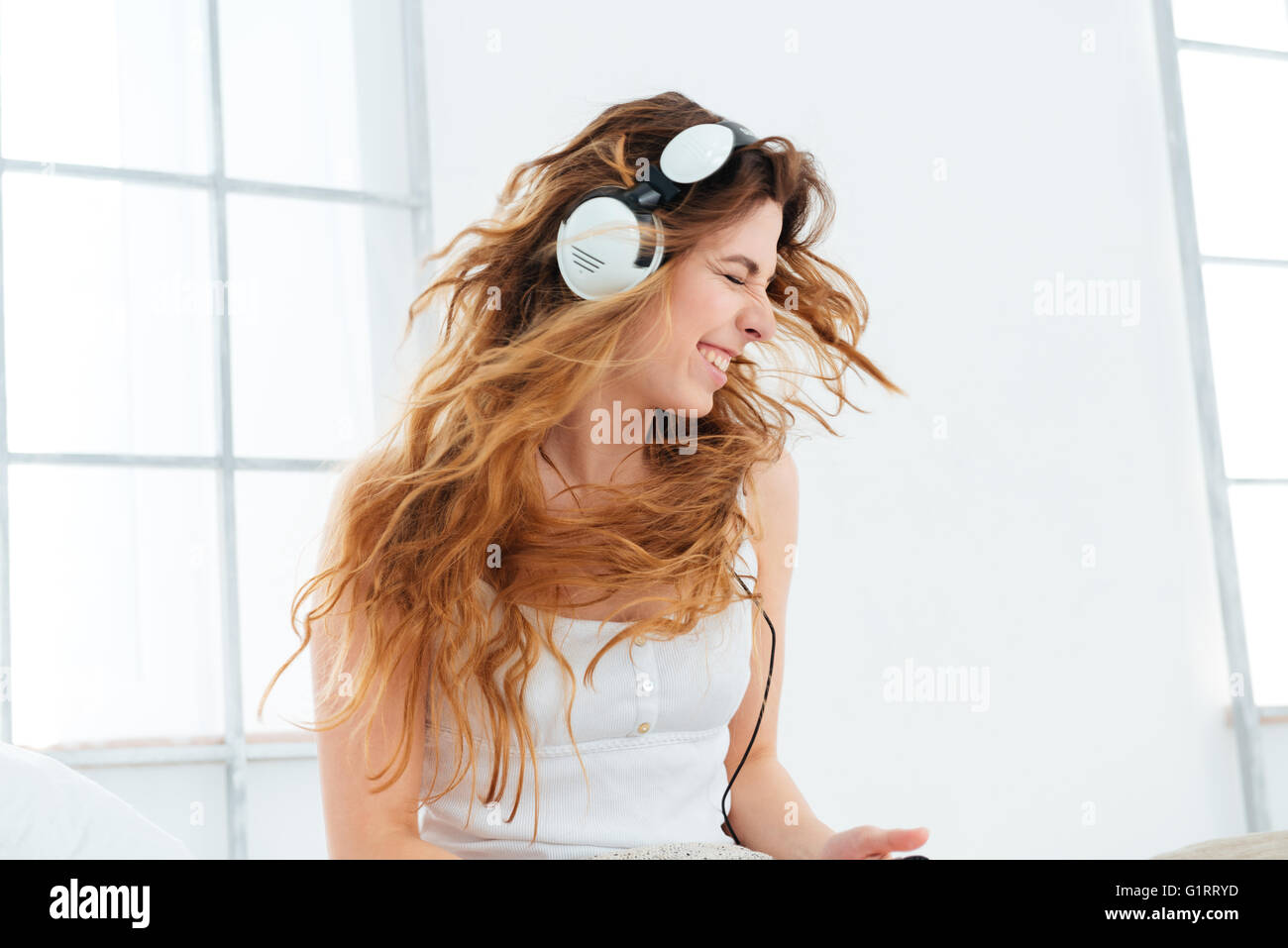 Cheerful woman listening music dans les écouteurs à la maison Banque D'Images