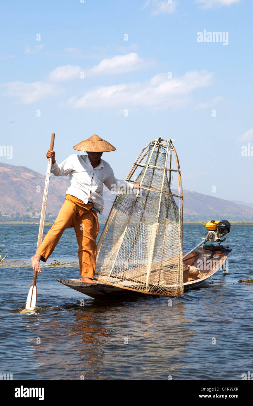 Sur le lac Inle, un pêcheur son bateau à rames avec une jambe sur un mouvement acrobatique (Birmanie). Pêcheur à la nasse sur le lac Inlé. Banque D'Images