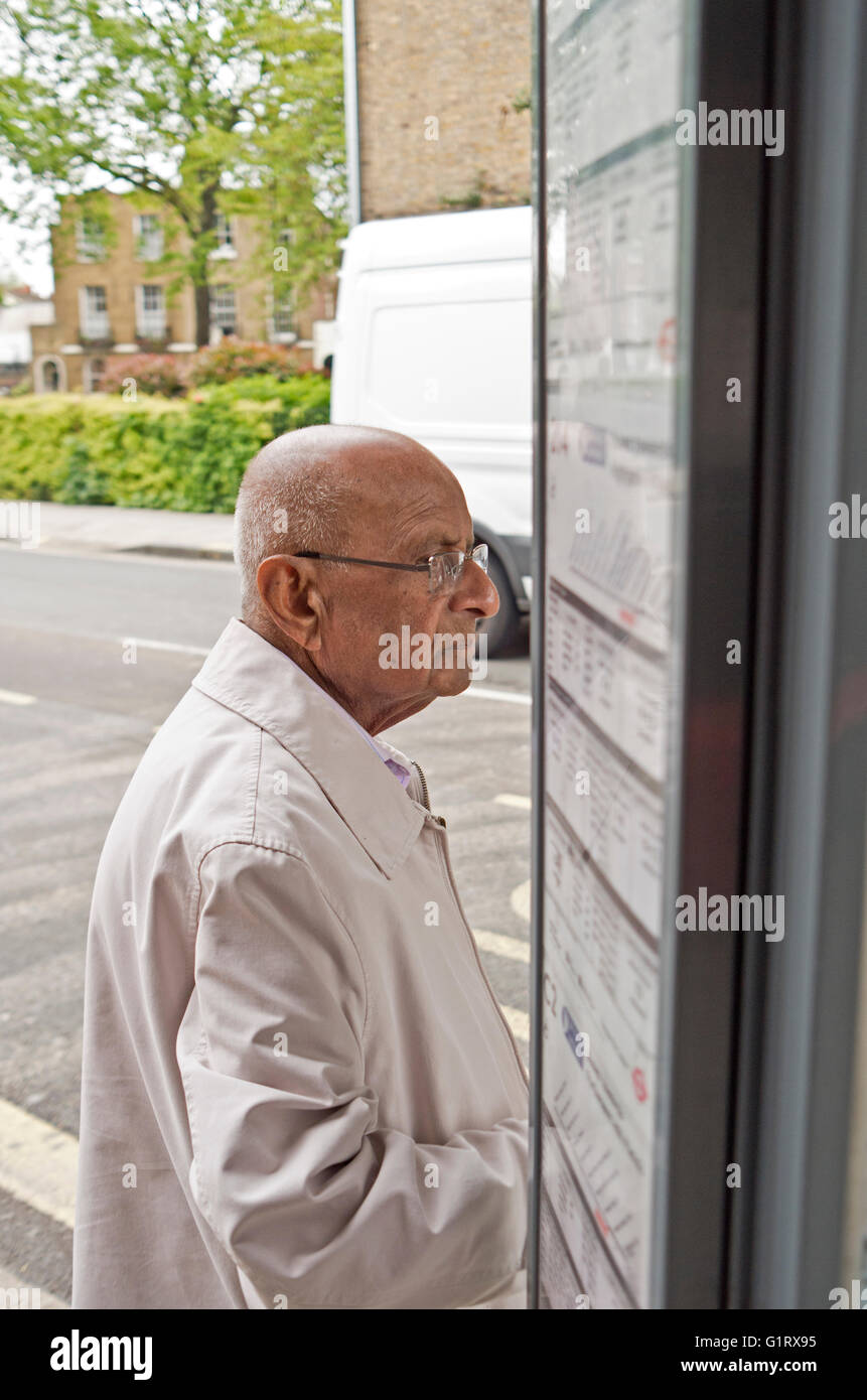 Un monsieur âgé attend à un arrêt d'autobus à Londres. Banque D'Images