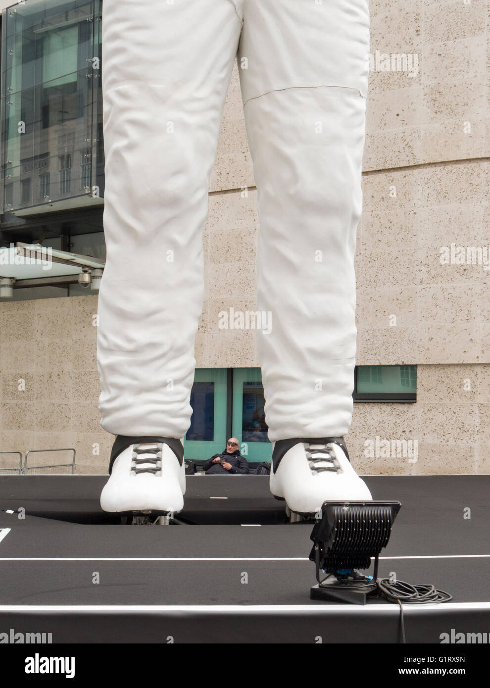 Un garde de sécurité à l'extérieur de la BBC, photographiés entre les pieds d'un grand modèle de Stig le mystère du pilote de Top Gear. Banque D'Images
