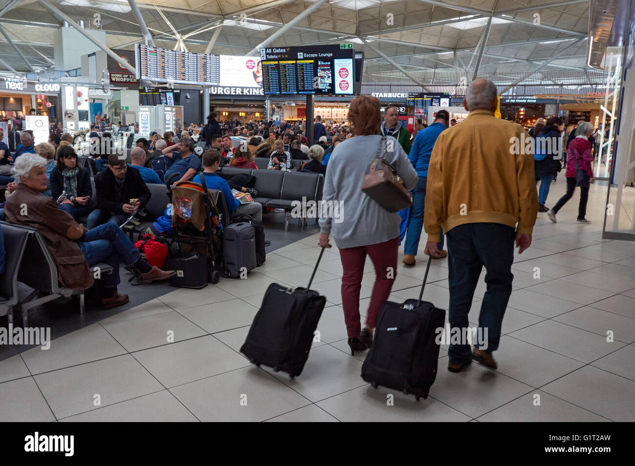 Passagers attendant dans le salon de départ de l'aéroport de Londres Stansted, Angleterre Royaume-Uni Banque D'Images