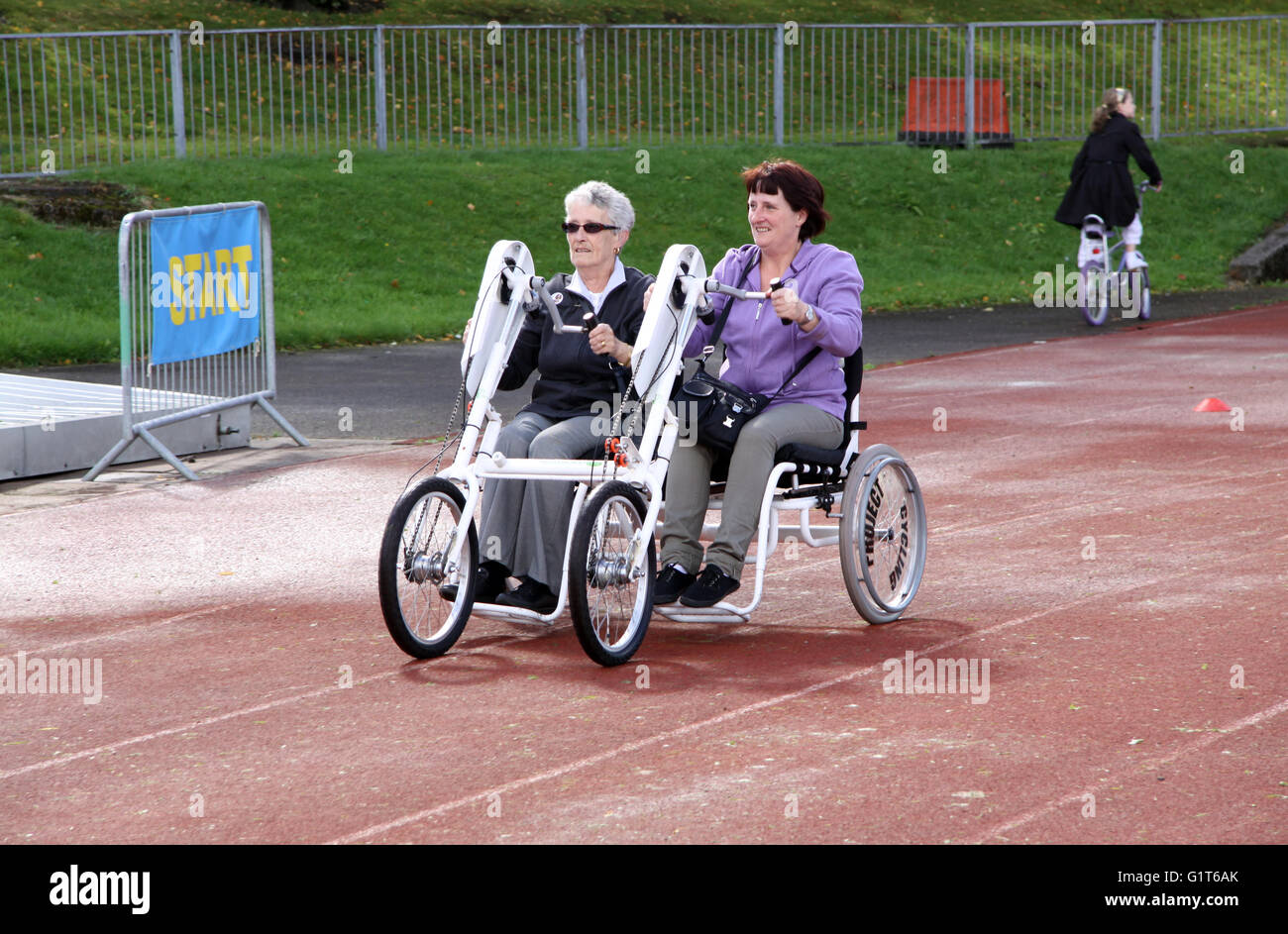 Deux dames à cheval sur quatre roues d'un vélo pour une double événement de collecte de fonds de bienfaisance à Bolton, Greater Manchester, Angleterre, Royaume-Uni Banque D'Images