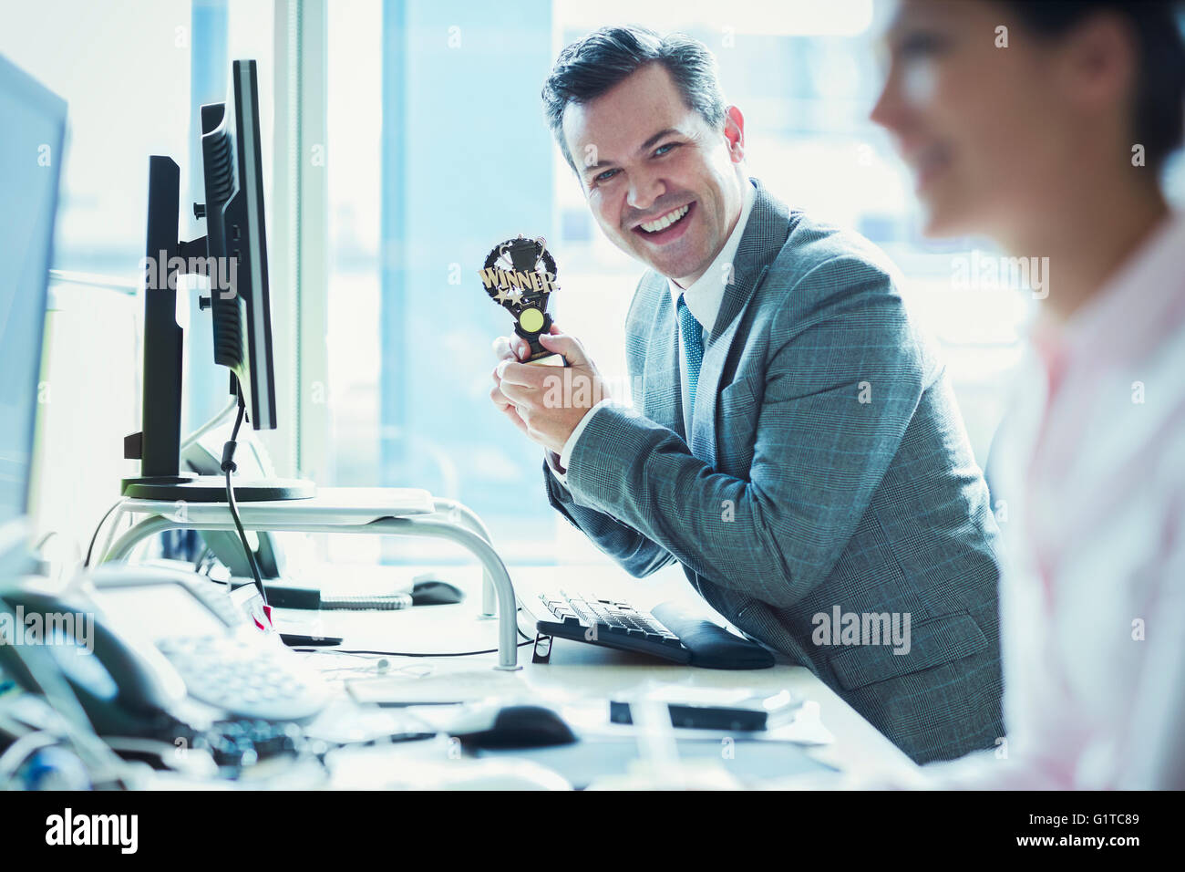 Portrait of enthusiastic woman holding trophy winner at desk in office Banque D'Images