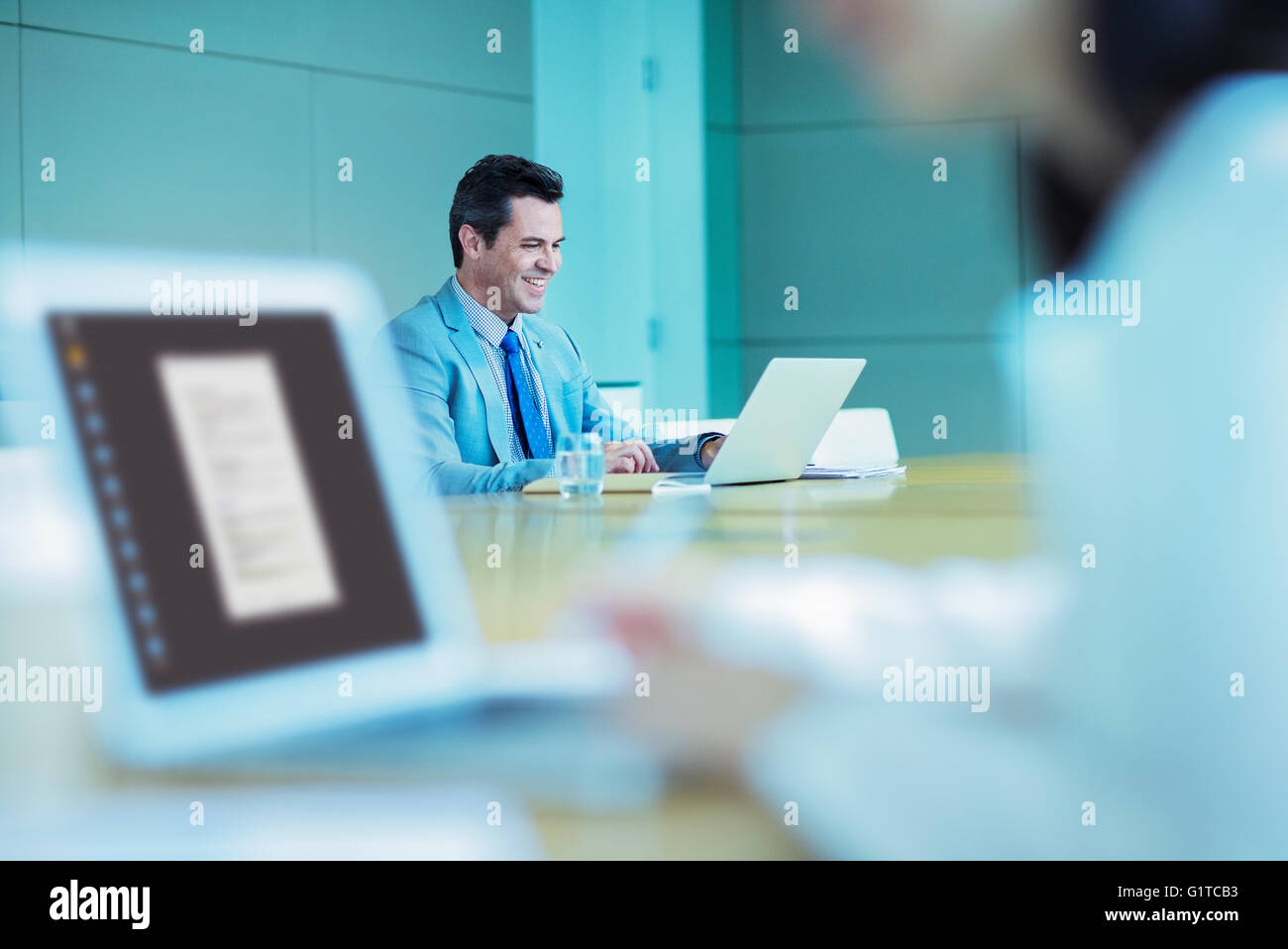 Smiling businessman working at laptop dans la salle de conférence Banque D'Images