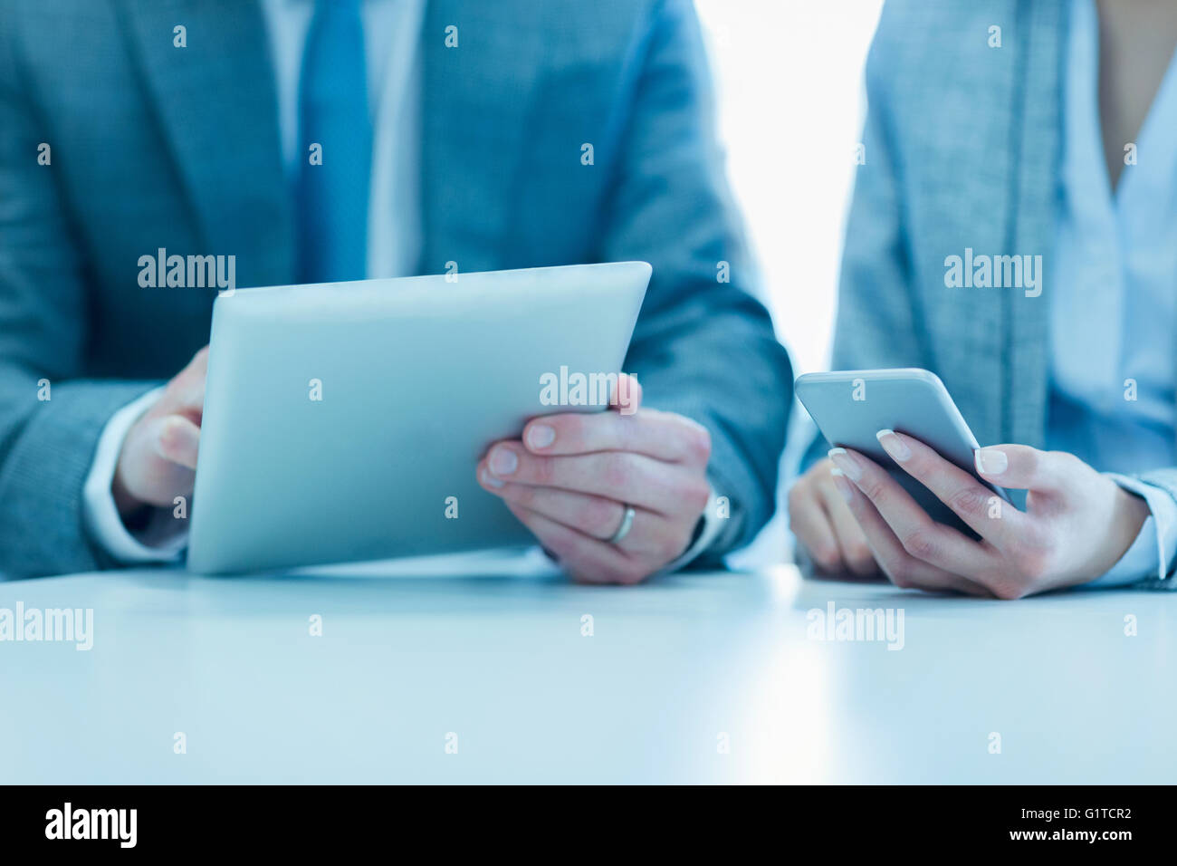 Businessman and businesswoman using digital tablet and cell phone Banque D'Images