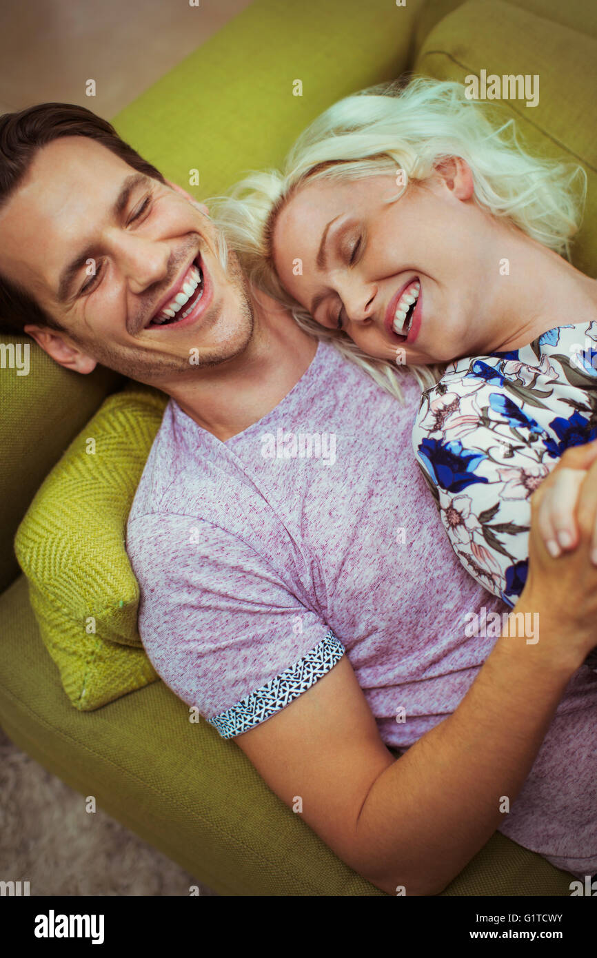Rire affectueux couple laying on sofa with eyes closed Banque D'Images
