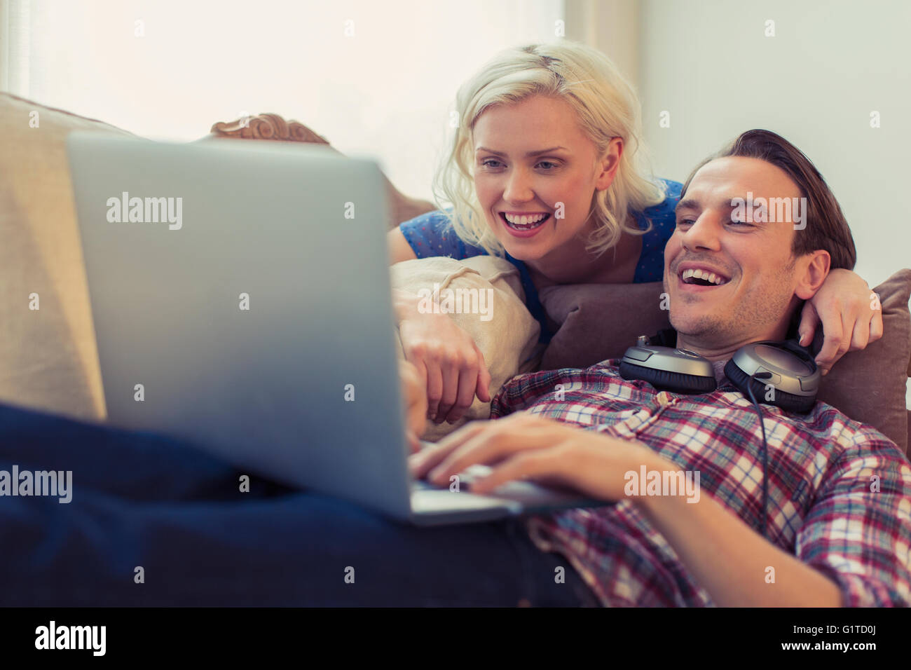 Smiling couple using laptop on salon canapé Banque D'Images