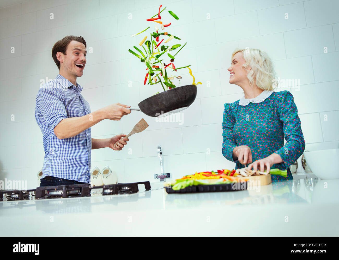 Surpris couple cooking renversant les légumes dans la poêle dans la cuisine Banque D'Images