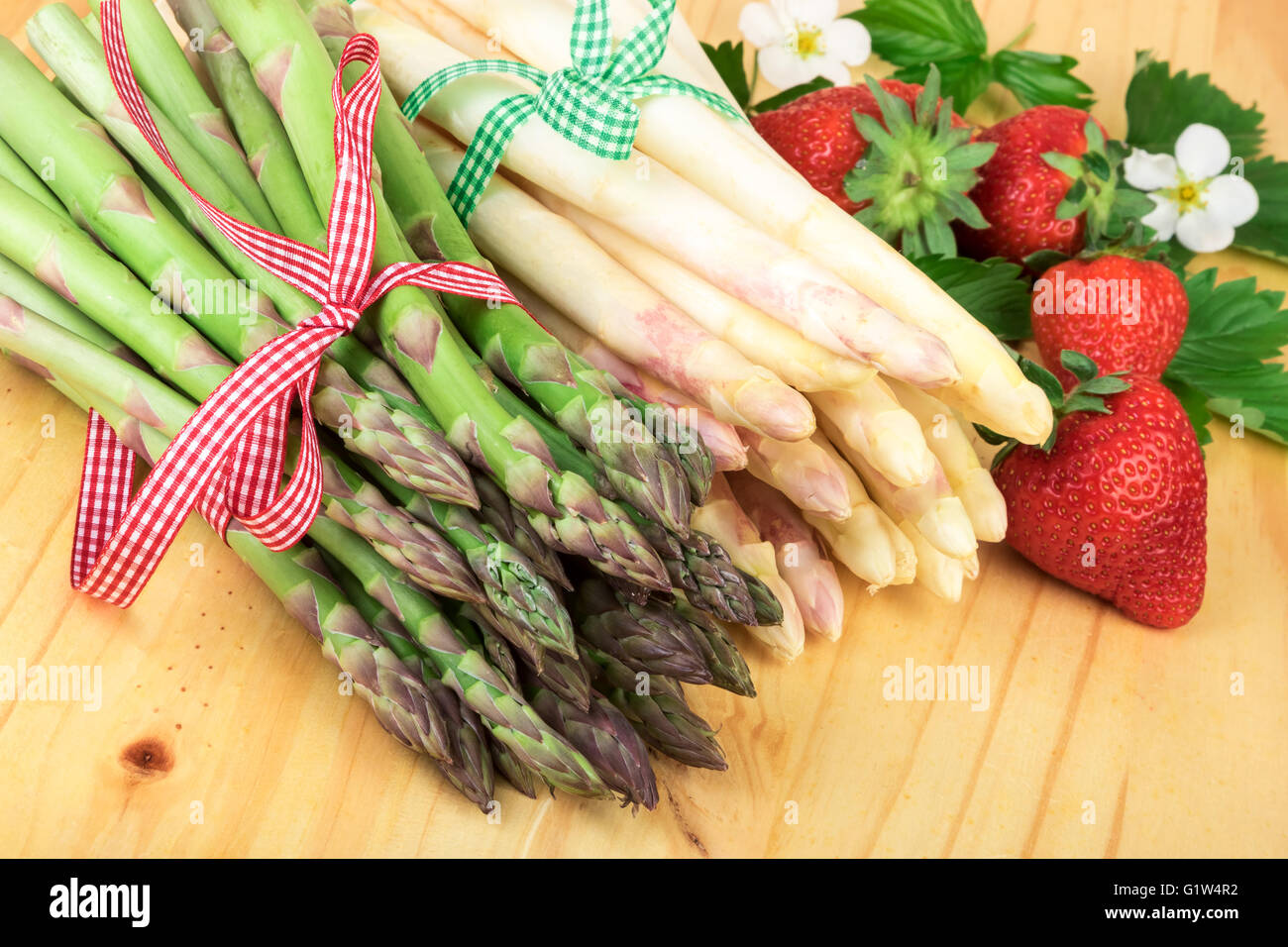 Vert blanc asperges aux fraises fraîches sur bois lumineux. Concept de cuisine saine. Banque D'Images