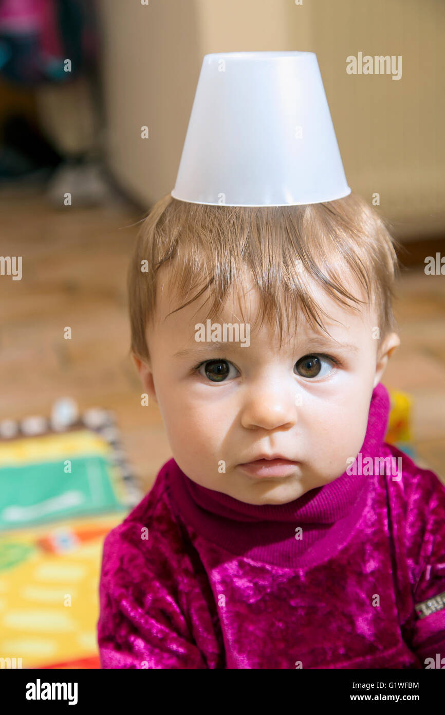 Portrait de drôles de petits d'un an bébé fille avec plastique verre sur la tête Banque D'Images