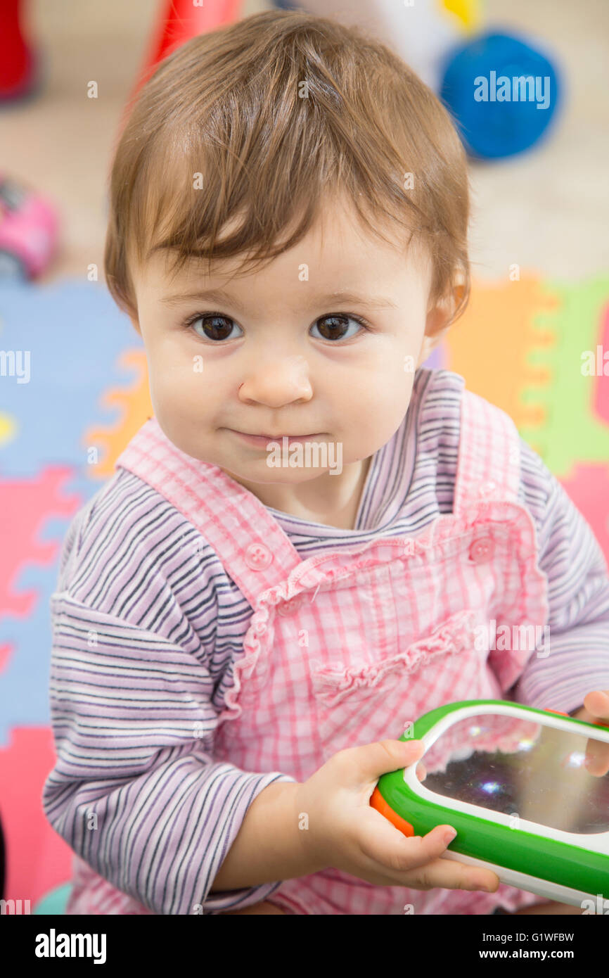 Portrait de l'adorable petite fille de un an avec jouet dans les mains et en souriant à l'écart Banque D'Images