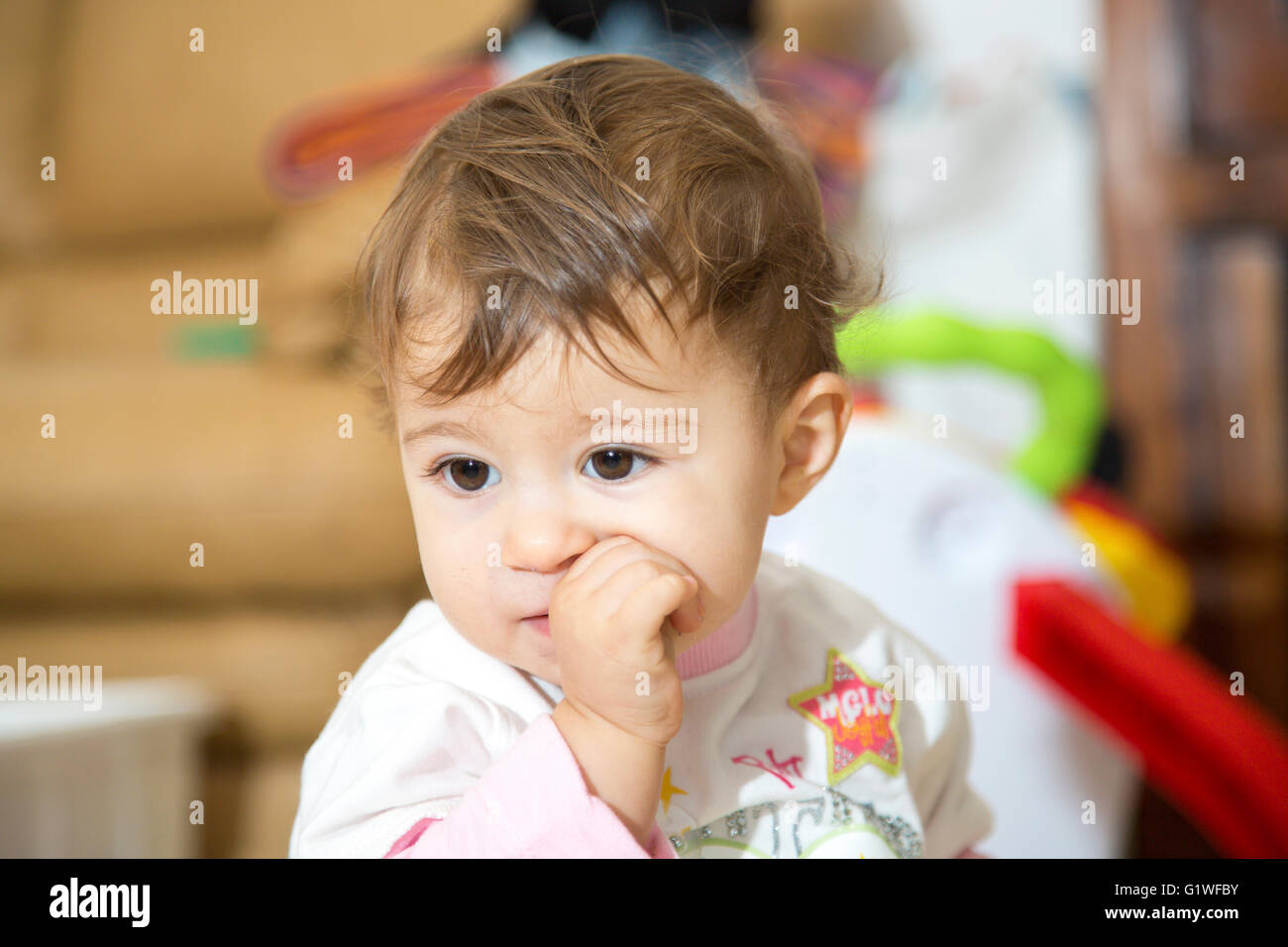 Un an cute baby with finger in mouth looking away Banque D'Images