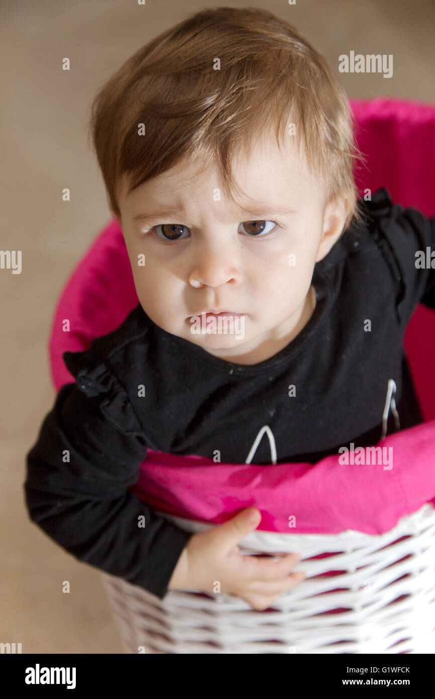 Portrait d'un an bébé fille dans un panier en osier à la colère Banque D'Images