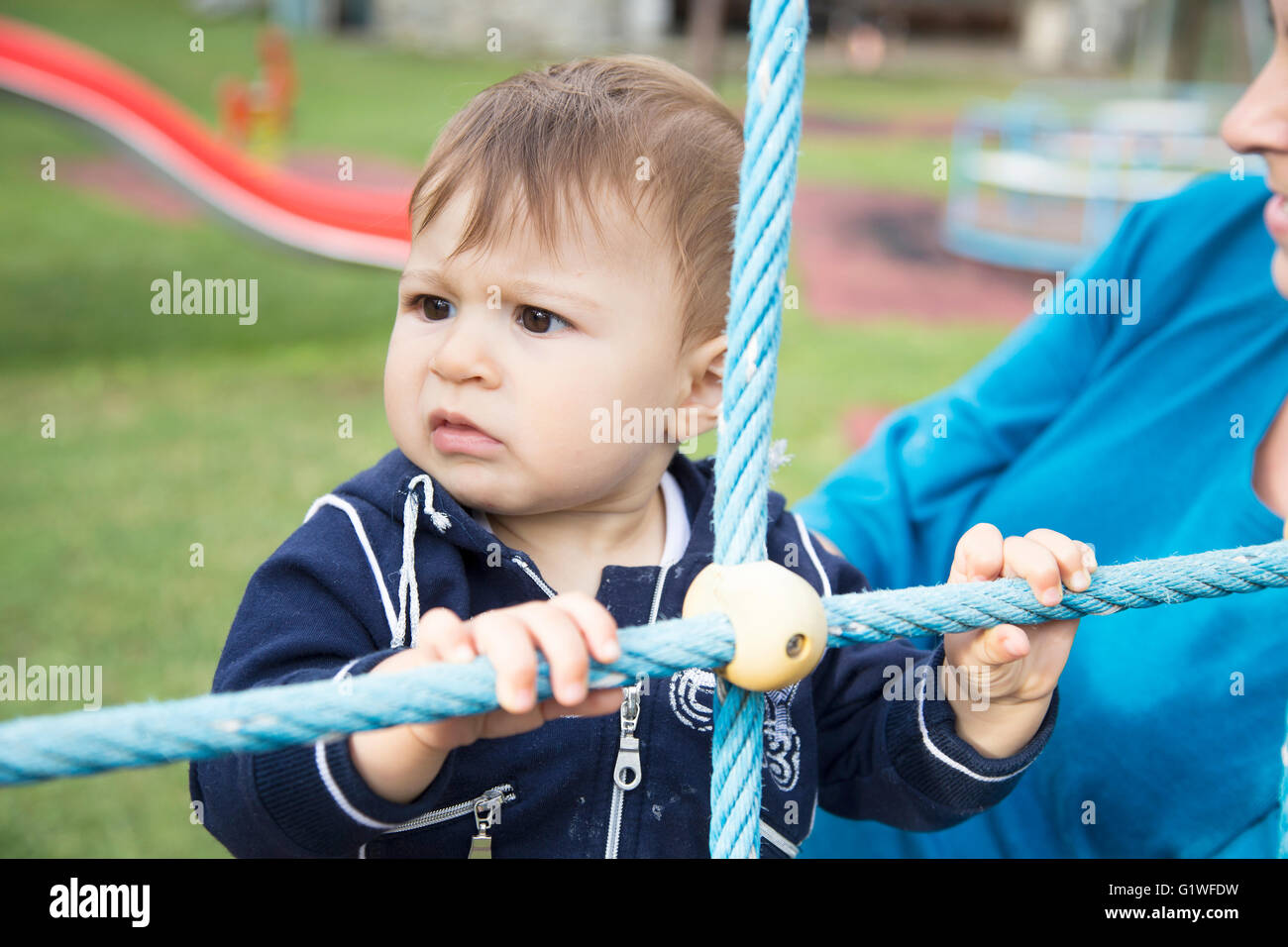 Portrait d'un bébé de l'année sérieux à l'écart tout en tenant la corde bleu à jeux pour enfants Banque D'Images
