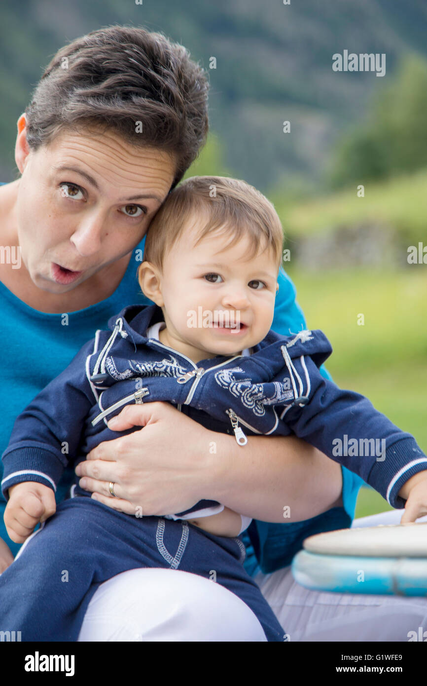 Drôle de mère faisant des grimaces à l'appareil photo tout en maintenant un beau bébé de l'année Banque D'Images