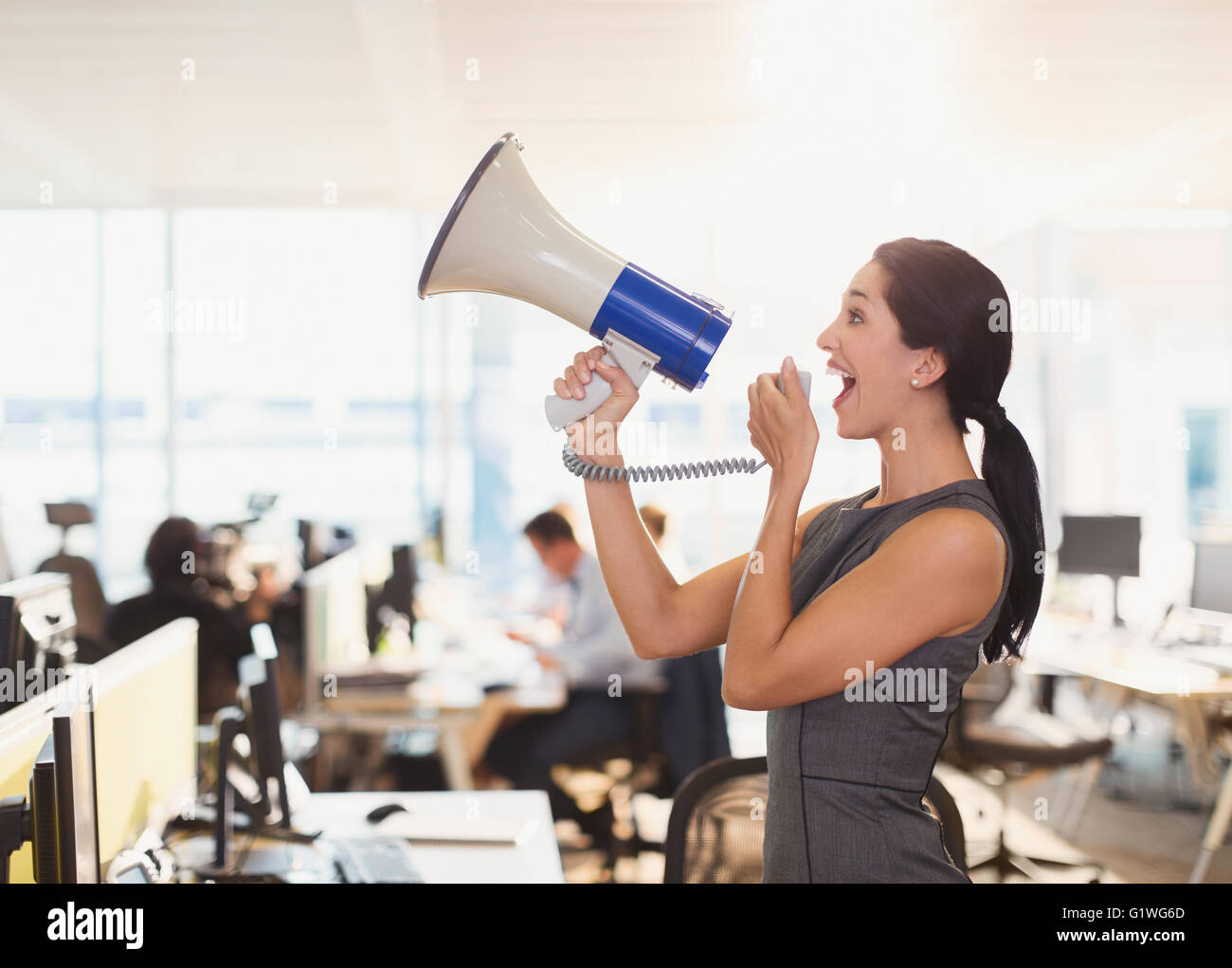 Businesswoman using megaphone exubérante in office Banque D'Images