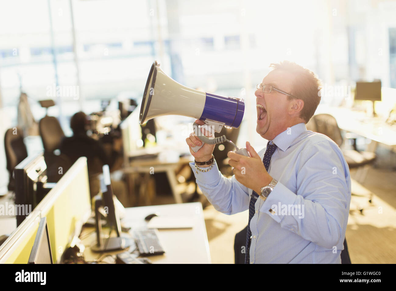 Homme d'exubérant de crier dans un mégaphone dans office Banque D'Images