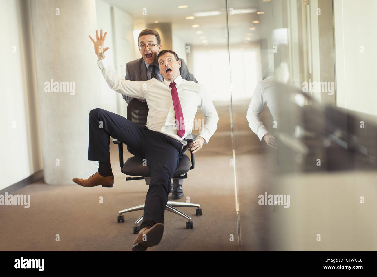 Collègue ludique businessman pushing down corridor en chaise de bureau Banque D'Images