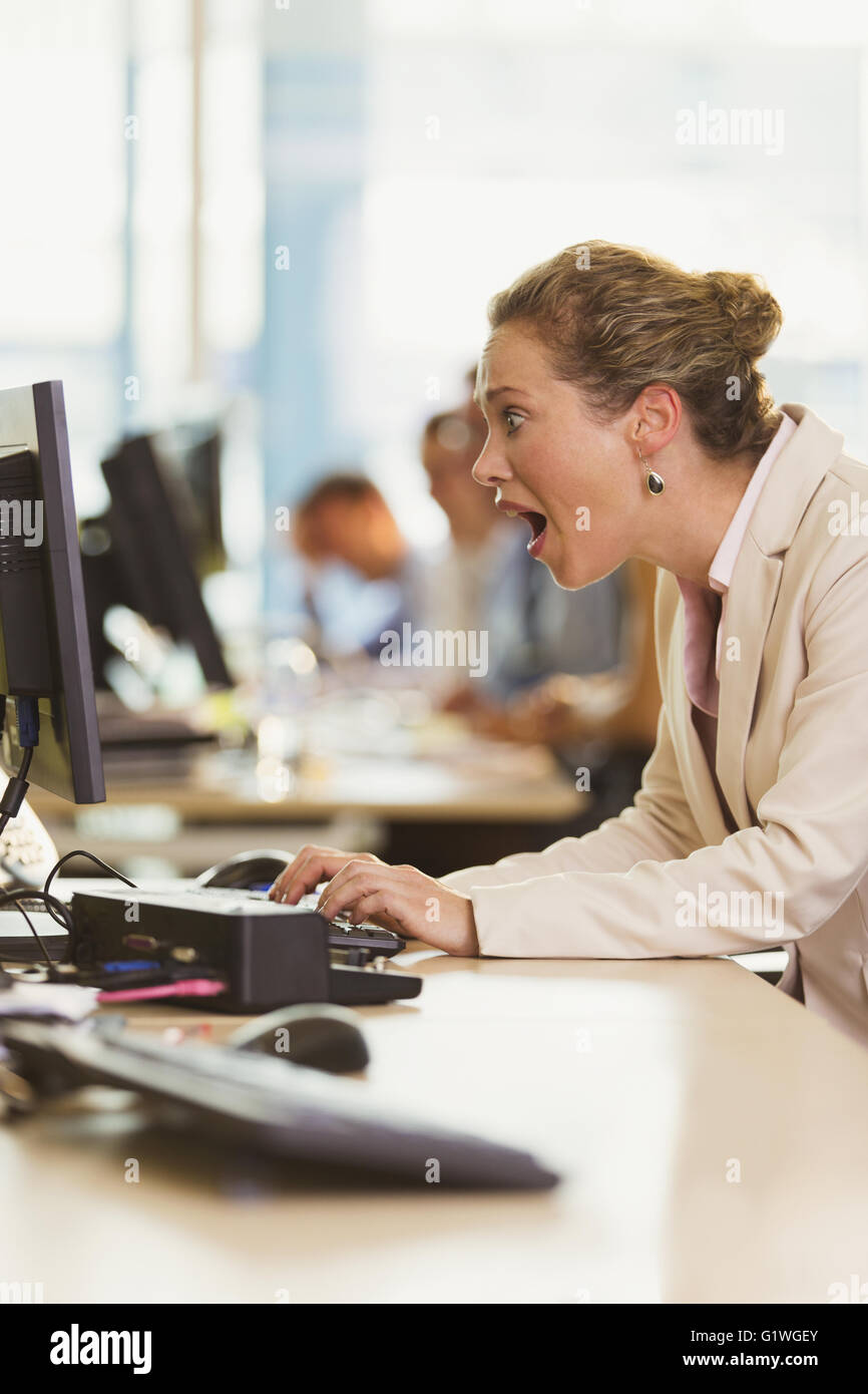 Choqué businesswoman working at computer in office Banque D'Images