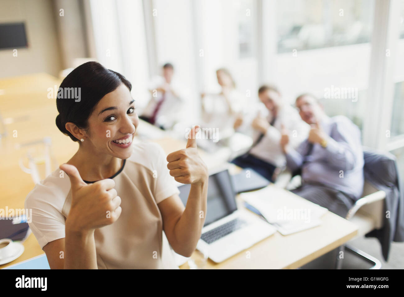 Portrait confident businesswoman et collègues gesturing thumbs-up dans la salle de conférence Banque D'Images