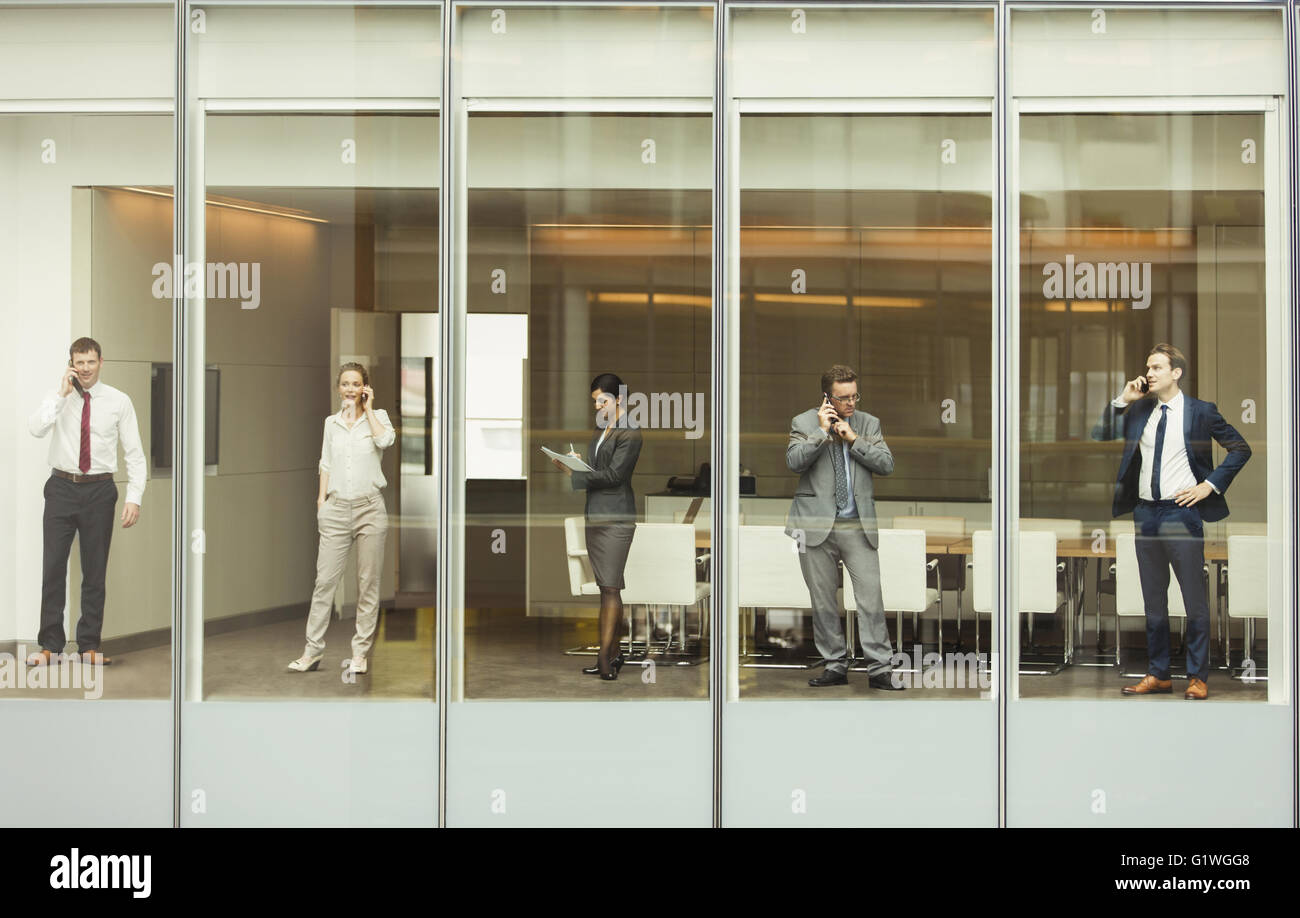Business people talking on cell phones et l'examen des formalités administratives de fenêtre salle de conférence Banque D'Images