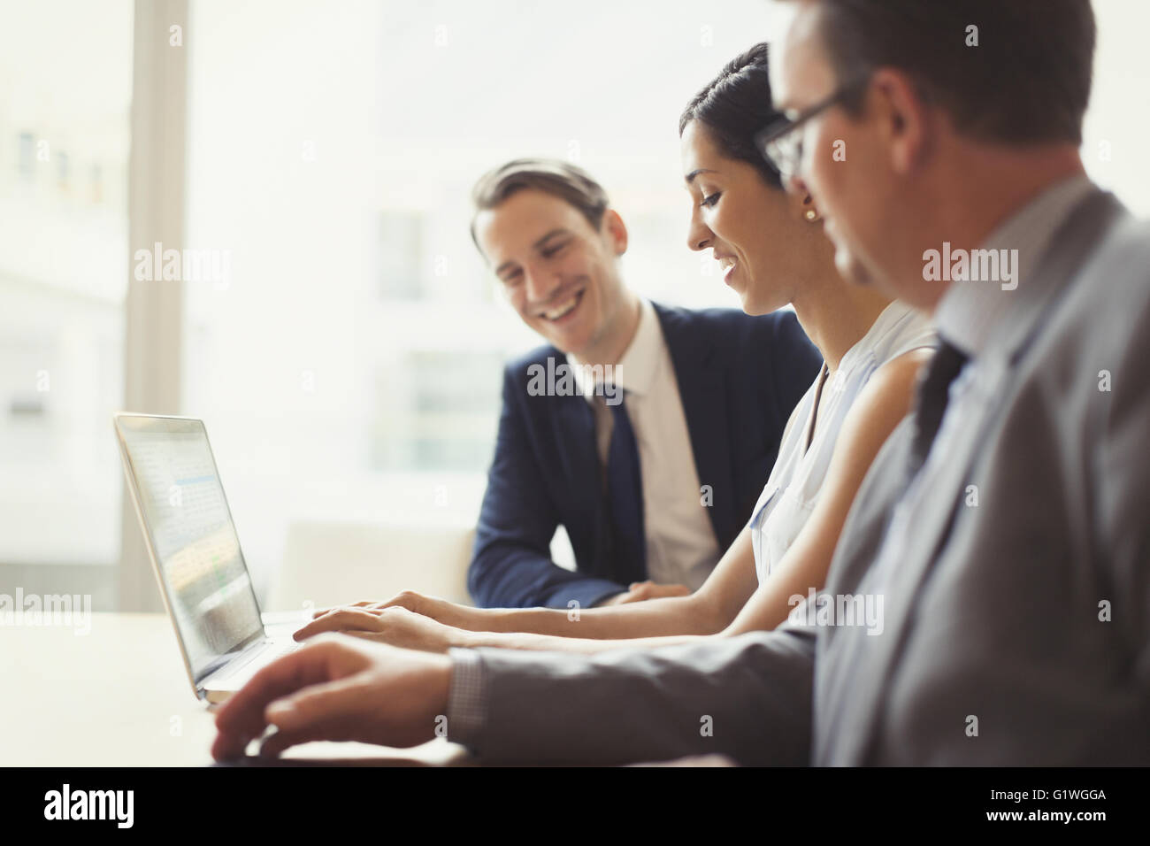 Smiling business people using laptop in conference room Banque D'Images