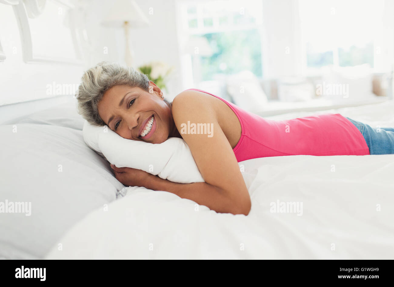Portrait of smiling mature woman laying on bed Banque D'Images