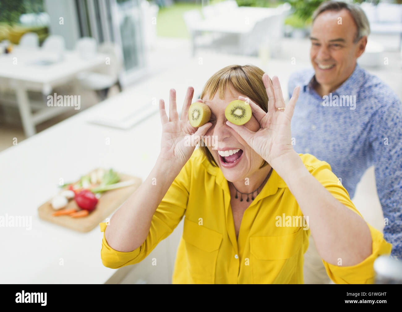 Portrait femme mature ludique couvrant les yeux avec les tranches de kiwi Banque D'Images