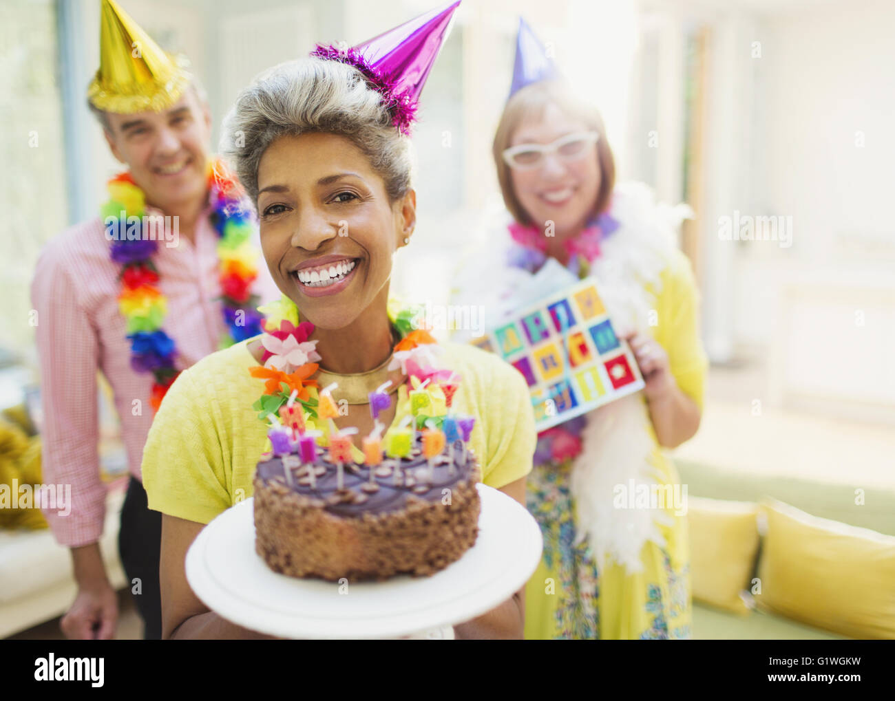 Portrait of smiling mature woman holding cake au chocolat avec des amis en arrière-plan Banque D'Images