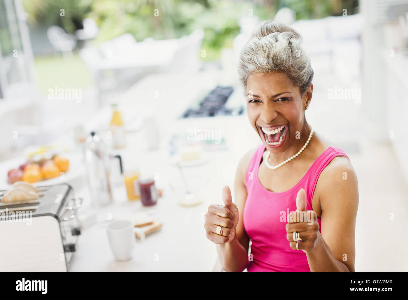 Confiance enthousiaste Portrait femmes mûres gesturing thumbs-up dans la cuisine Banque D'Images