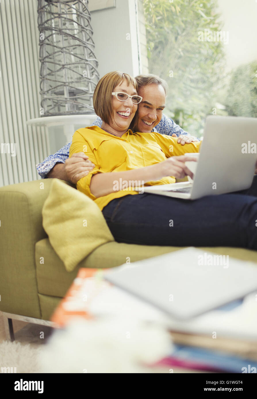 Smiling mature couple ordinateur portable sur salon canapé Banque D'Images