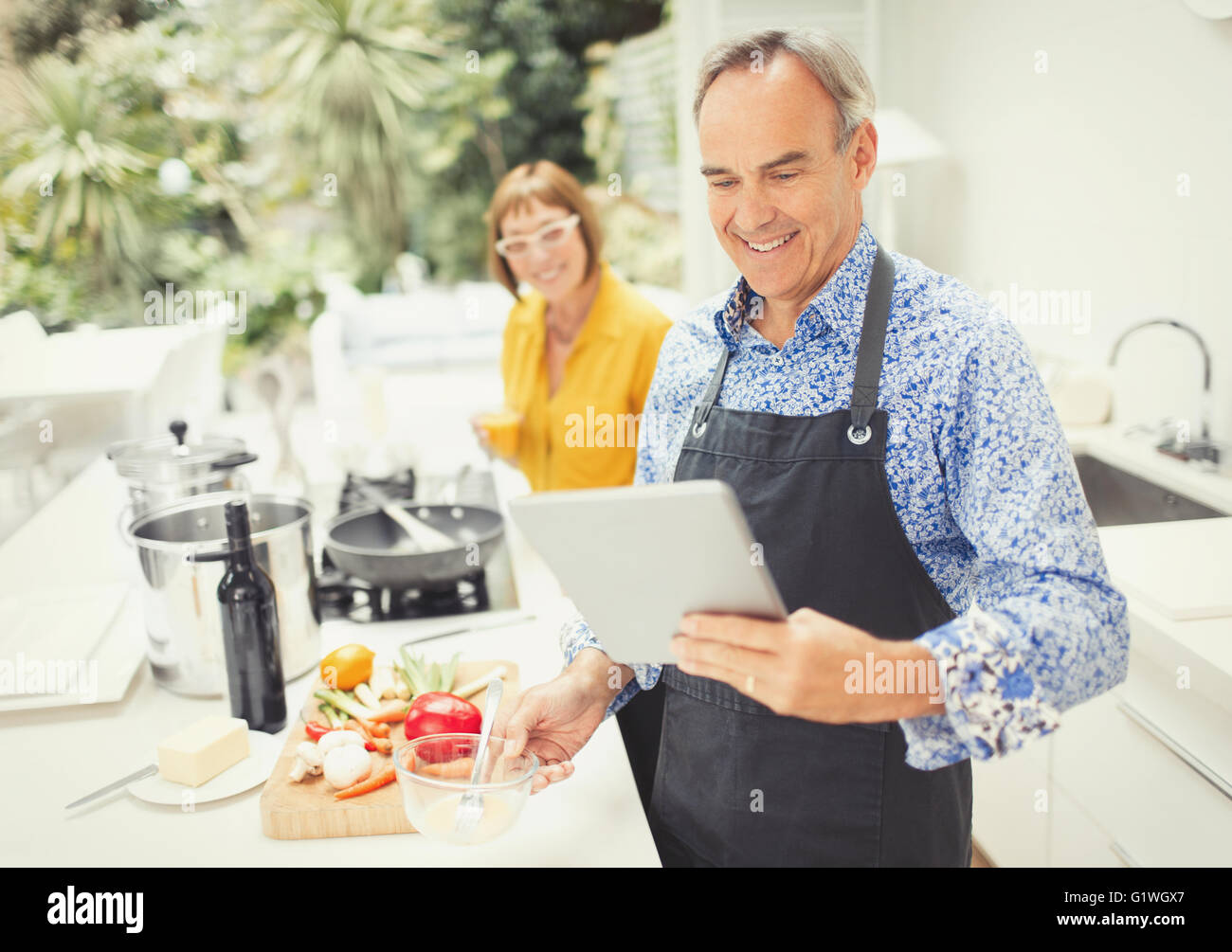 Young couple with digital tablet cooking in kitchen Banque D'Images