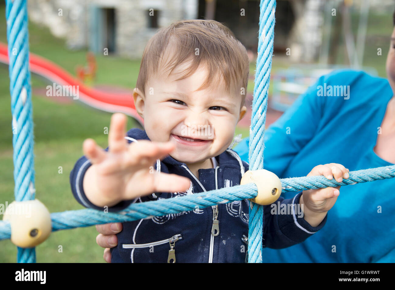 Un an baby girl tirant son bras et smiling at camera Banque D'Images