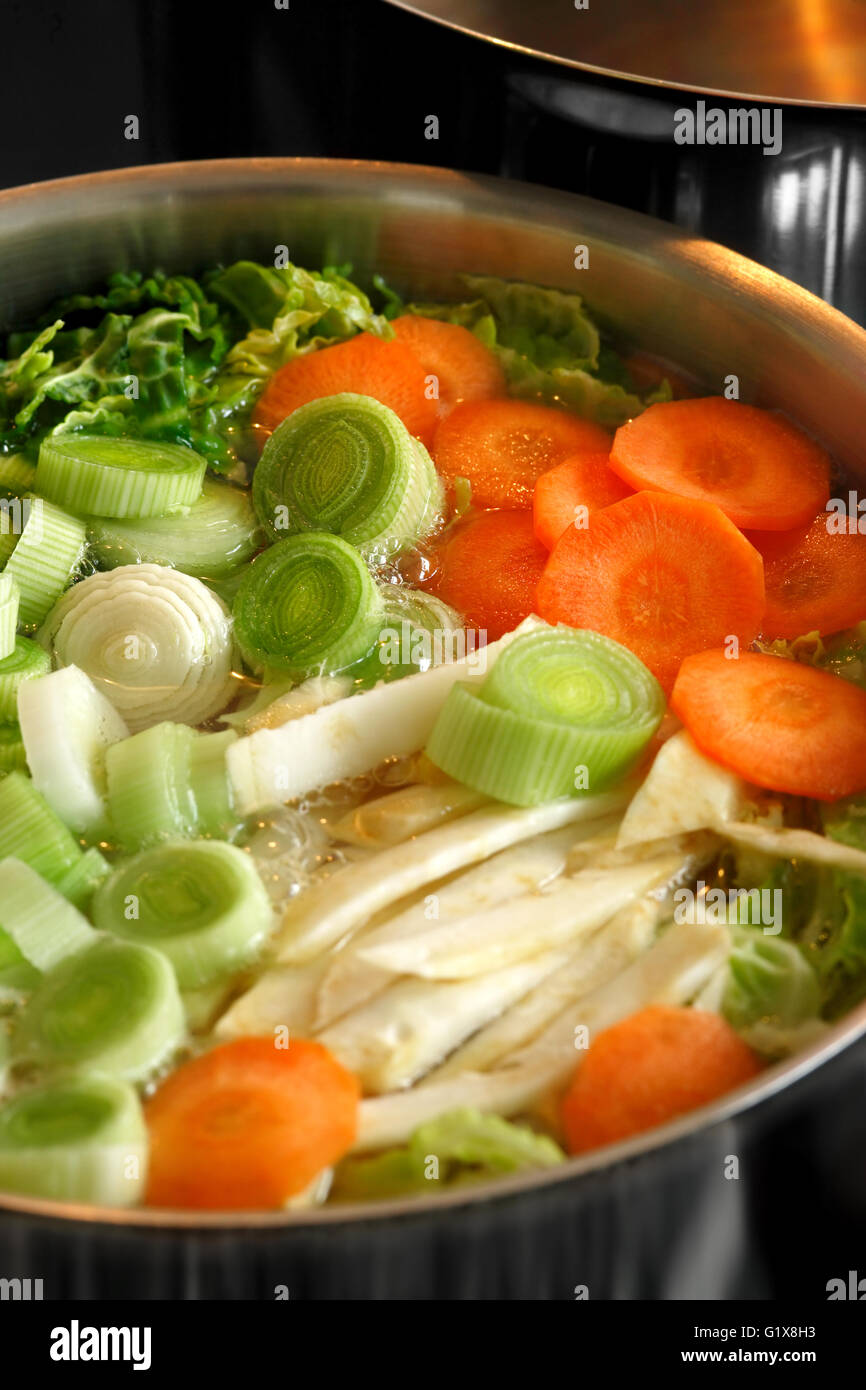Photo d'un grand pot de soupe de légumes l'ébullition sur le dessus d'une cuisinière. L'accent est sur le milieu de l'image. Banque D'Images