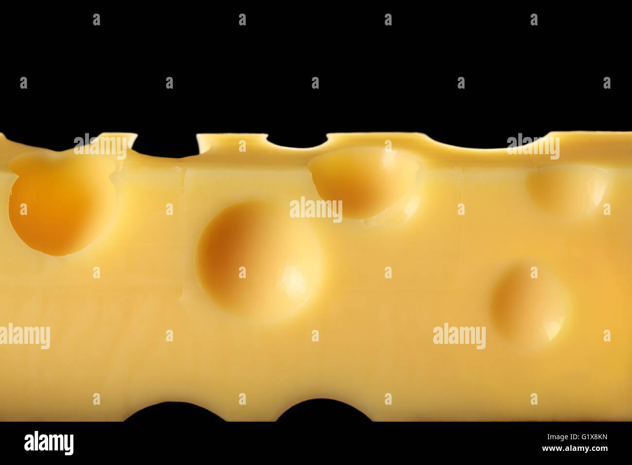 Macro photo d'un bloc de fromage Emmental de Suisse. Sur un fond noir rétroéclairé. Banque D'Images