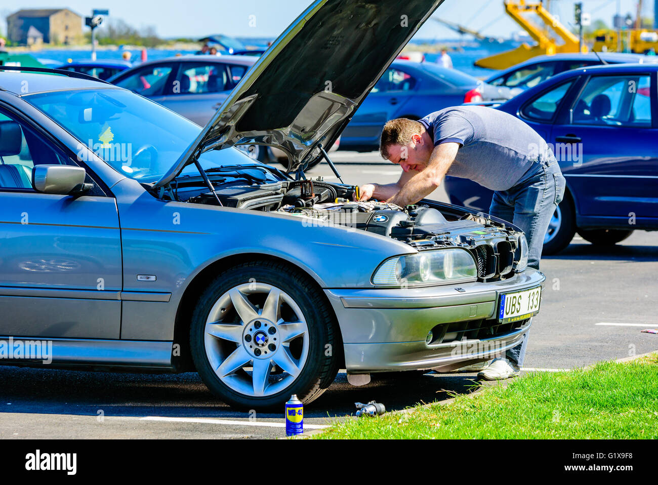 Karlskrona, Suède - mai 3, 2016 : personne de sexe masculin travaillant sous le capot d'une BMW 525 touring 2005 sur une aire de stationnement dans le port. H Banque D'Images