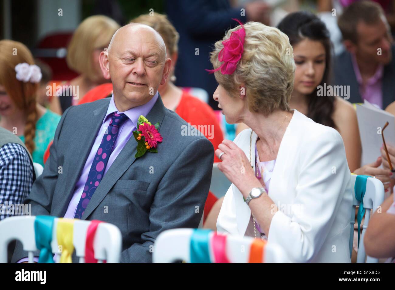 Mère et père de la mariée assis dans l'église attendant l'arrivée de la mariée pour un mariage en plein air. Banque D'Images