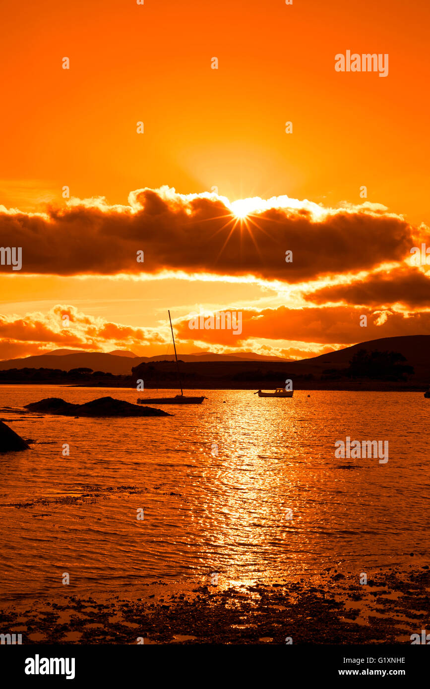 Bateaux dans une baie tranquille près de Kenmare, sur la manière dont l'Irlande sauvage de l'Atlantique avec un coucher du soleil orange Banque D'Images