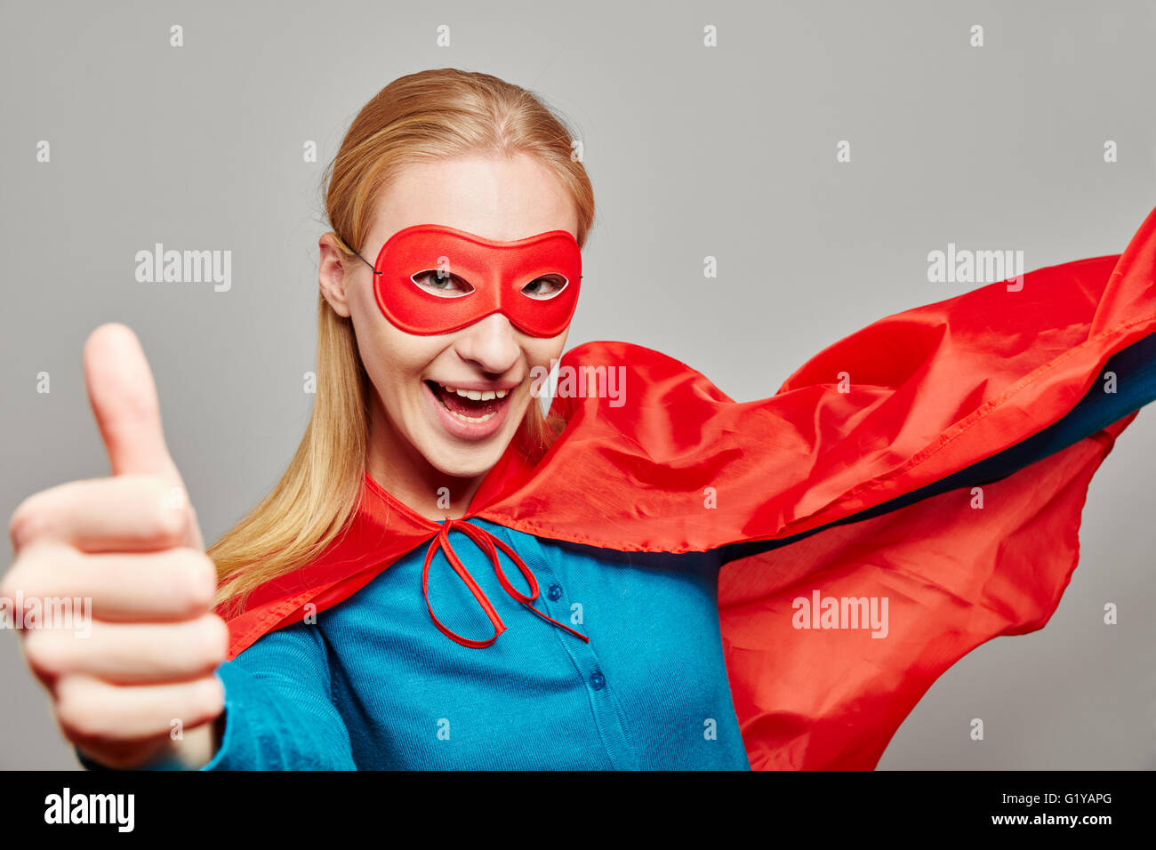Smiling woman habillé en super héros tenant son pouce vers le haut Banque D'Images
