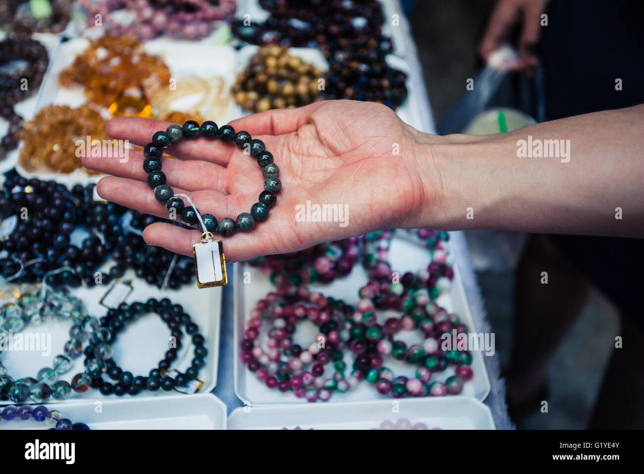 A woman's hand holding est un bracelet at a market stall Banque D'Images